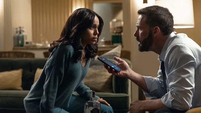 Ben Affleck sostiene un teléfono frente a Kerry Washington, sentada en un living.