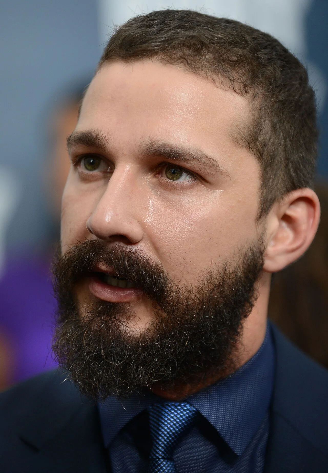 Retrato de Shia LaBeouf en 2014, con barba y traje oscuro.