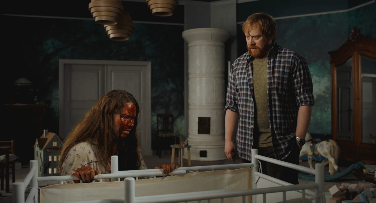 Seidi Haarla, con sangre en el rostro, se apoya en una cuna mientras Rupert Grint la mira.