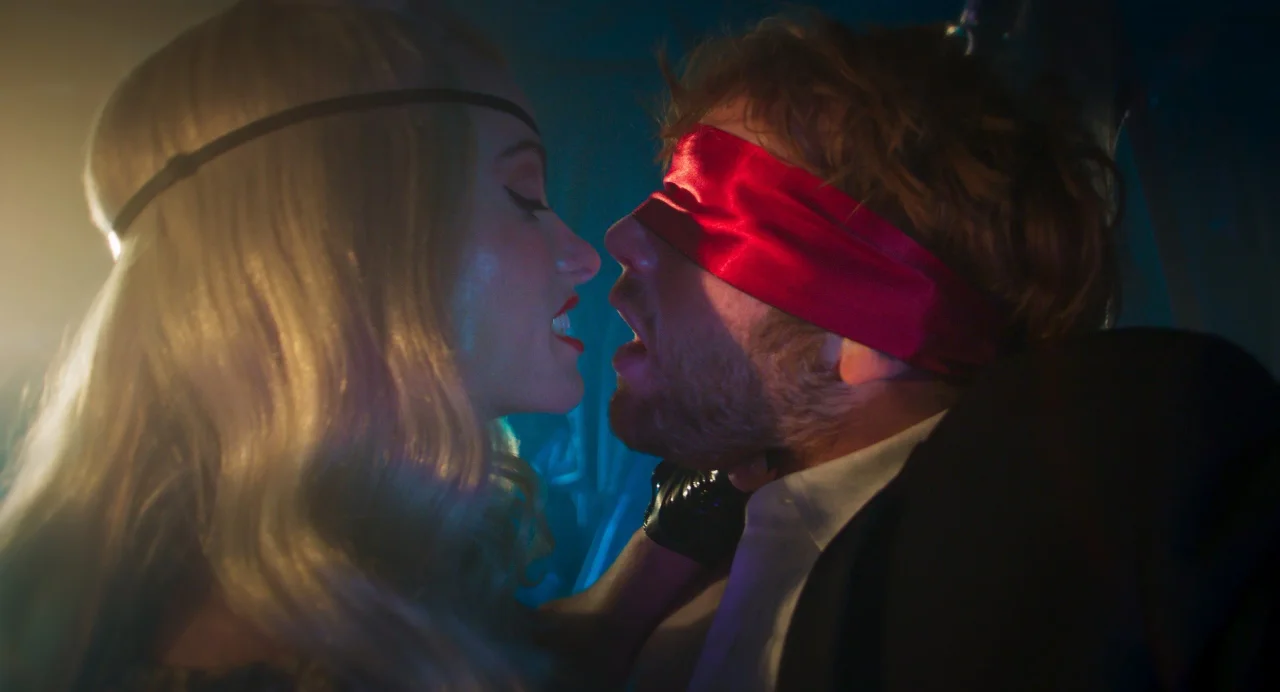 Olivia Wilde se acerca a Cooper Hoffman, que lleva una venda roja sobre los ojos, en Quiero tu sexo.
