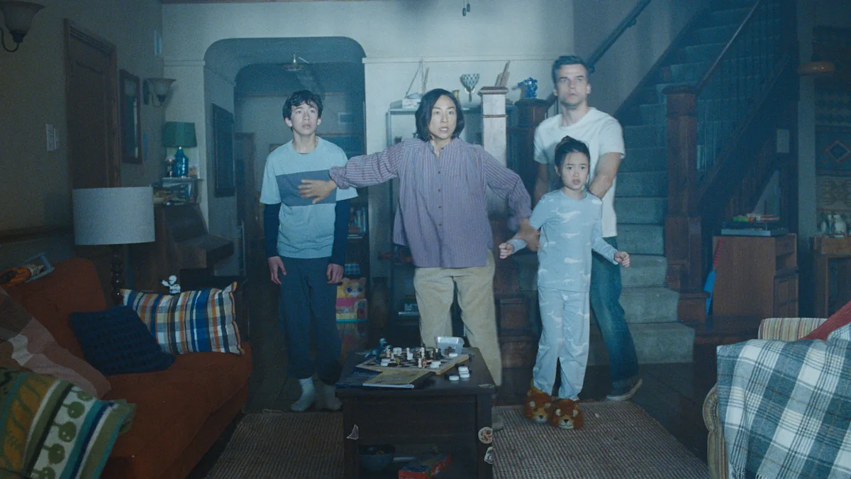 Cuatro integrantes de una familia permanecen juntos en el living y miran hacia fuera de cuadro, tensos.