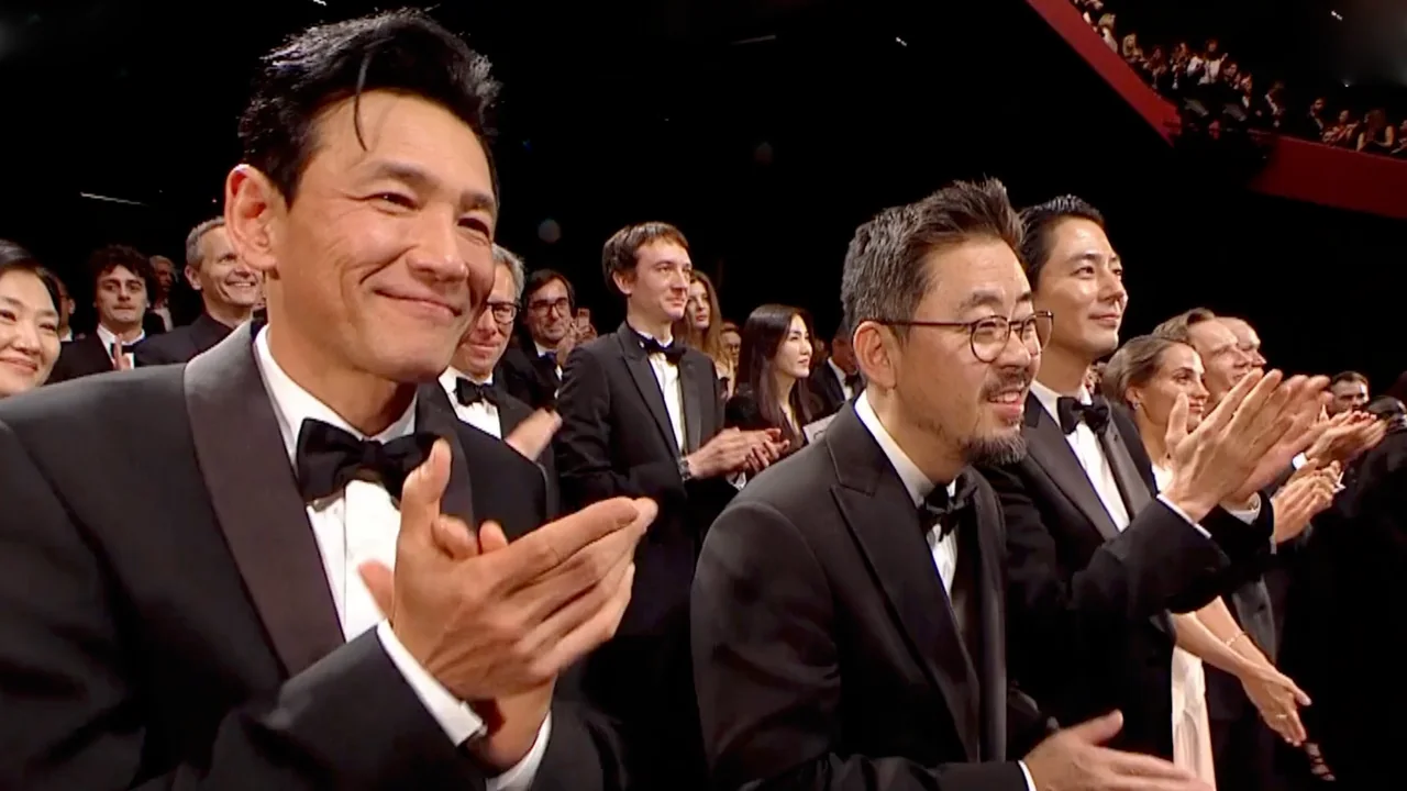 Na Hong-jin y otros integrantes del equipo de Hope aplauden desde sus butacas en una sala.