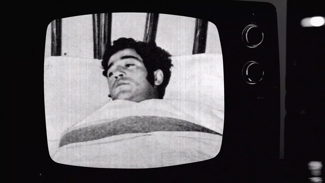 Un televisor muestra el rostro de un hombre recostado en una imagen en blanco y negro de El caso Llanca.