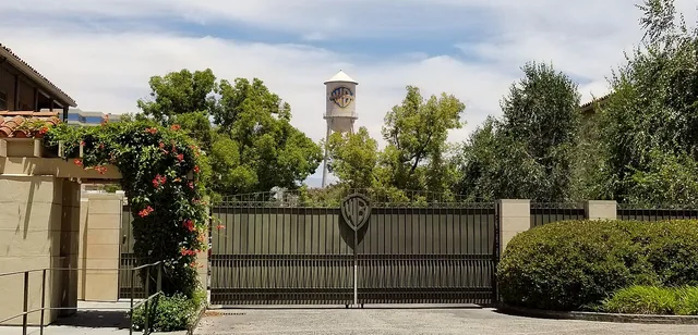 Vista del portón de Warner Bros. Studios en Burbank, con la torre de agua detrás de árboles.